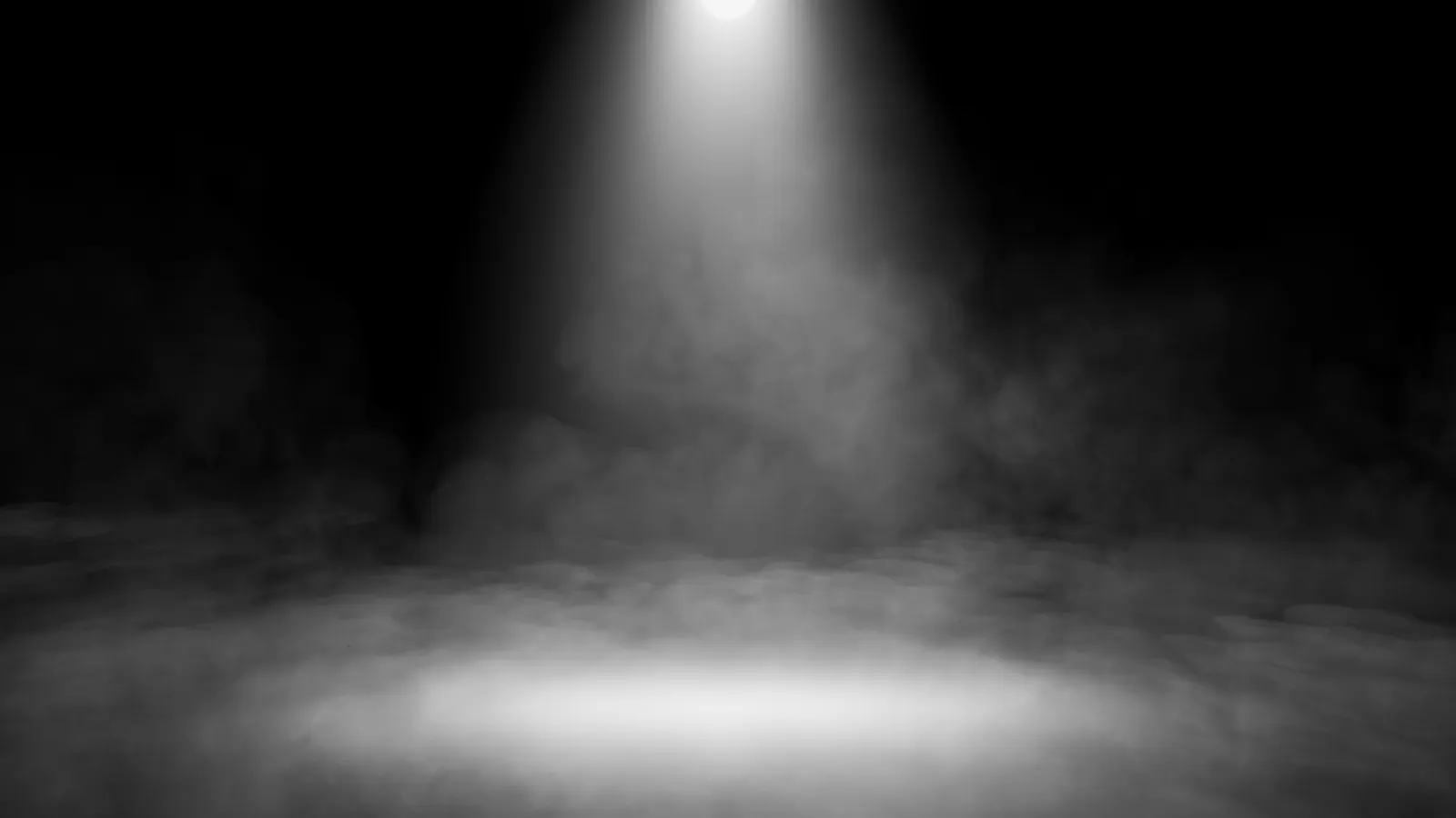 Empty stage with spotlight shining through misty fog on dark black background for dramatic effect