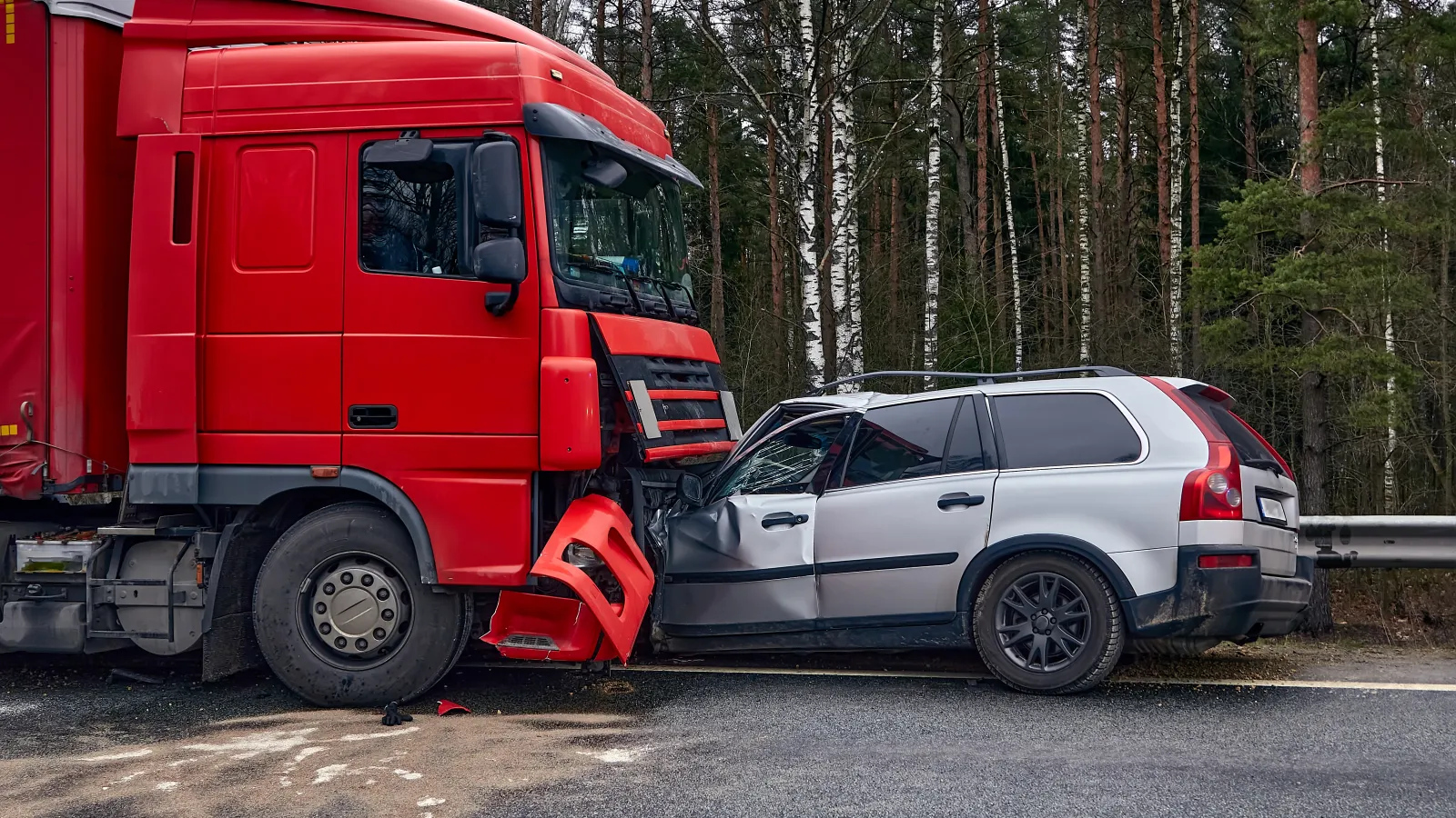 Red semi-truck and silver SUV involved in a front-end collision on a rural road with trees in the background