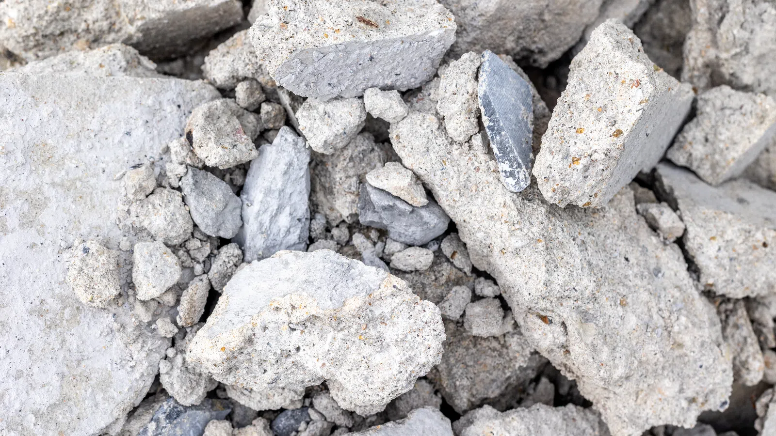 Pile of broken gray concrete rubble with mixed small and large fragments on the ground.