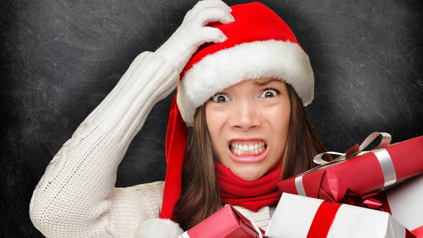 a girl in a santa hat and scarf in front of a chalkboard