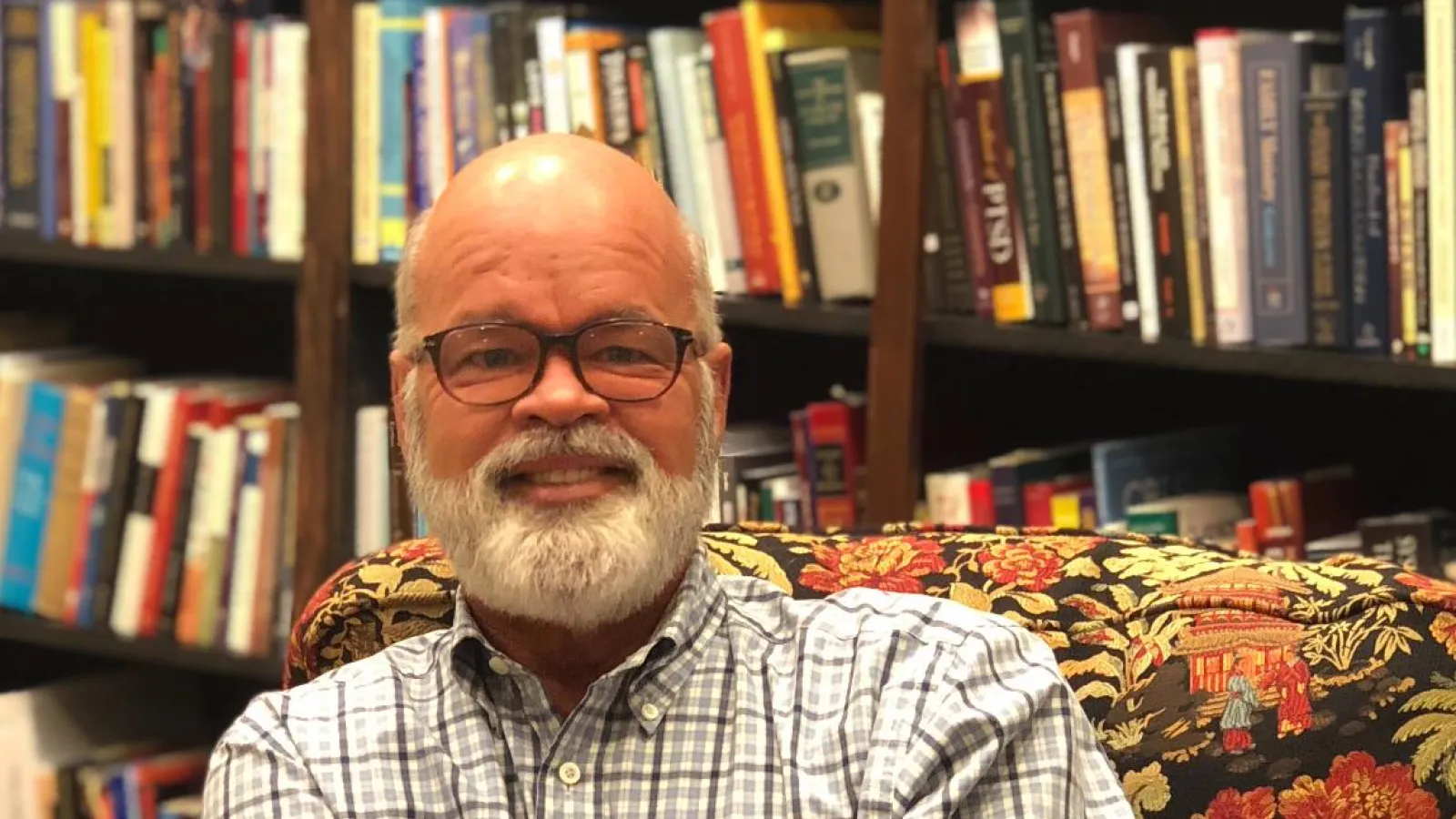 a man with a beard in front of a book shelf