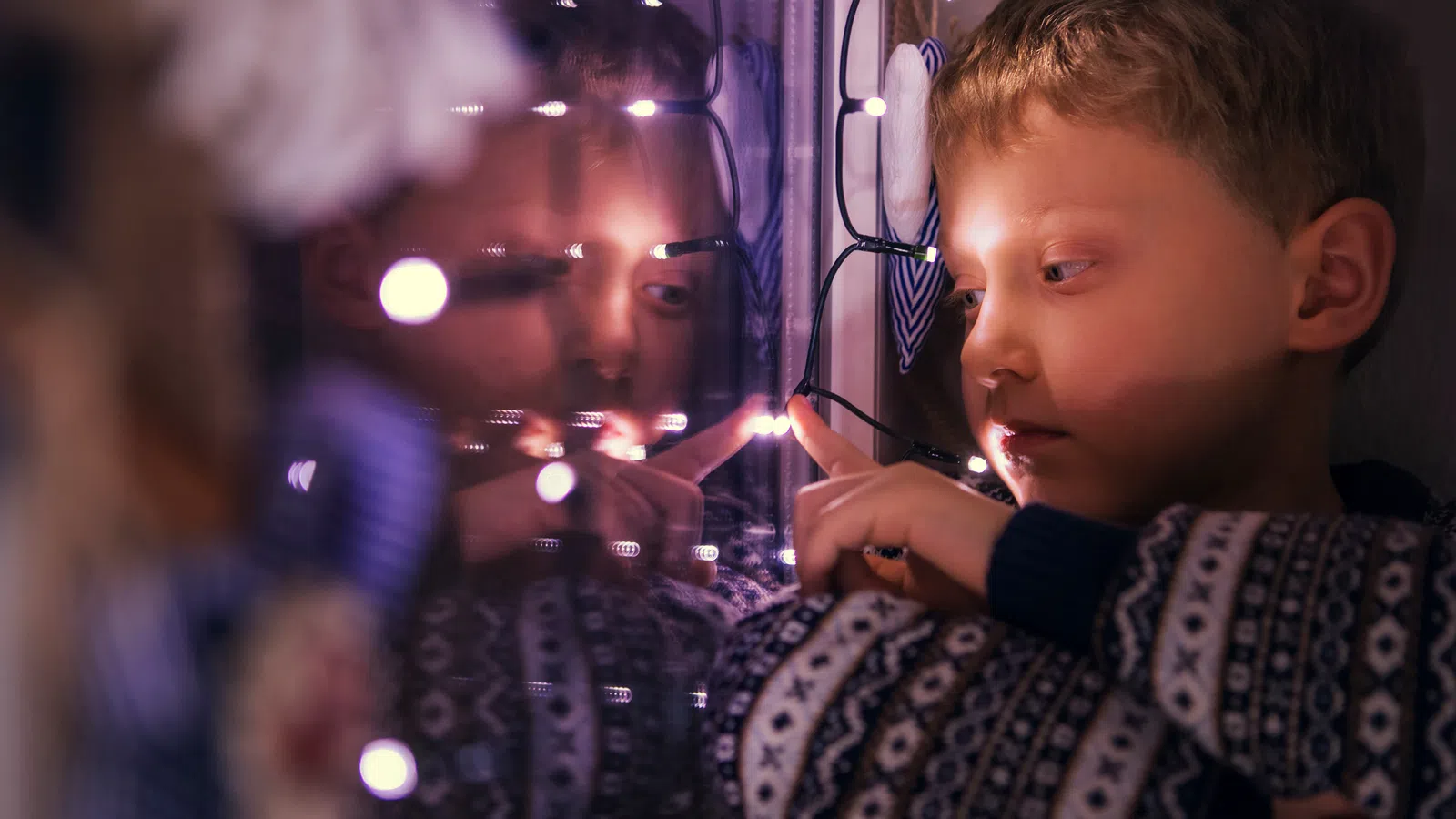 A child looking out a window at Christmas lights during his holiday visitation.