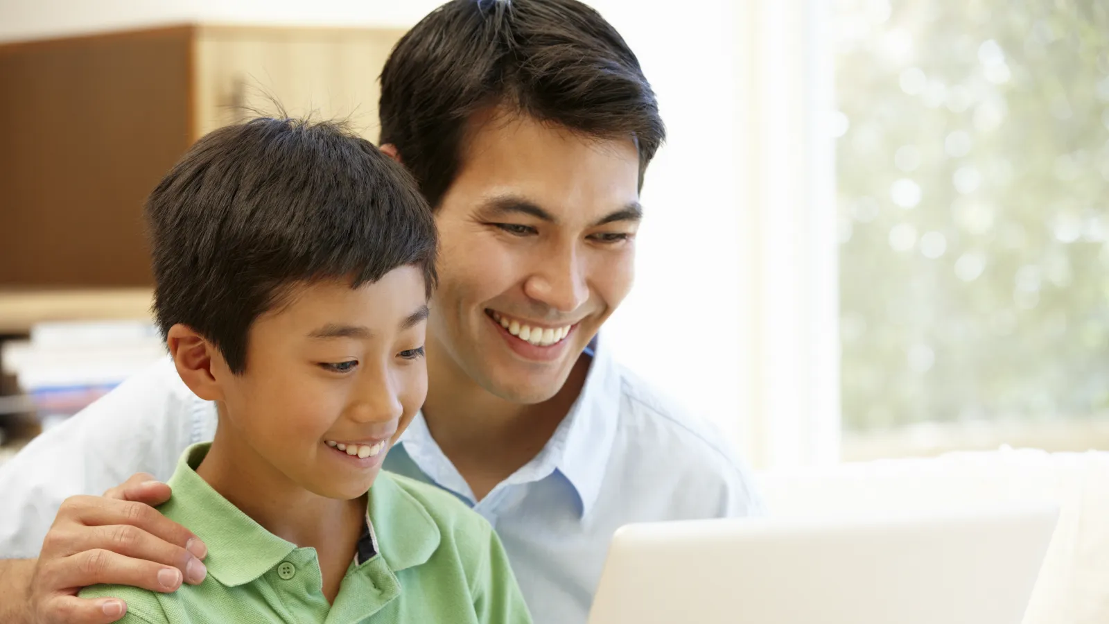 a person and a boy looking at a laptop