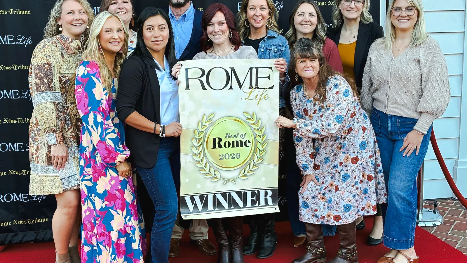 Group of people posing on red carpet holding a Best of Rome 2026 Winner banner with overlaid text.