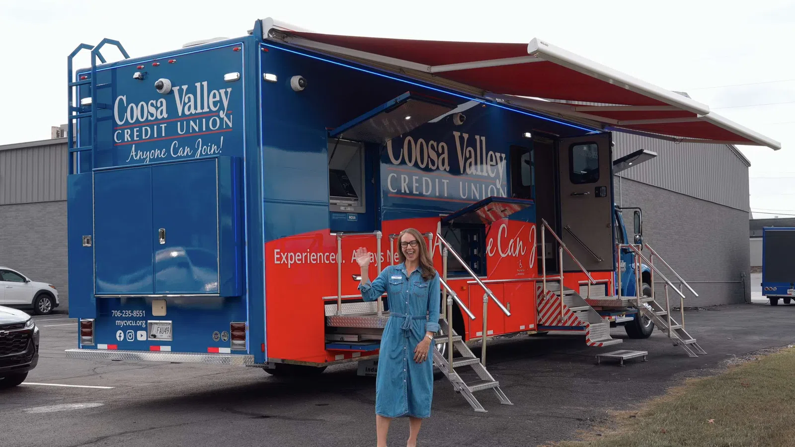 Woman standing in front of a Coosa Valley Credit Union mobile branch vehicle with blue and red exterior.
