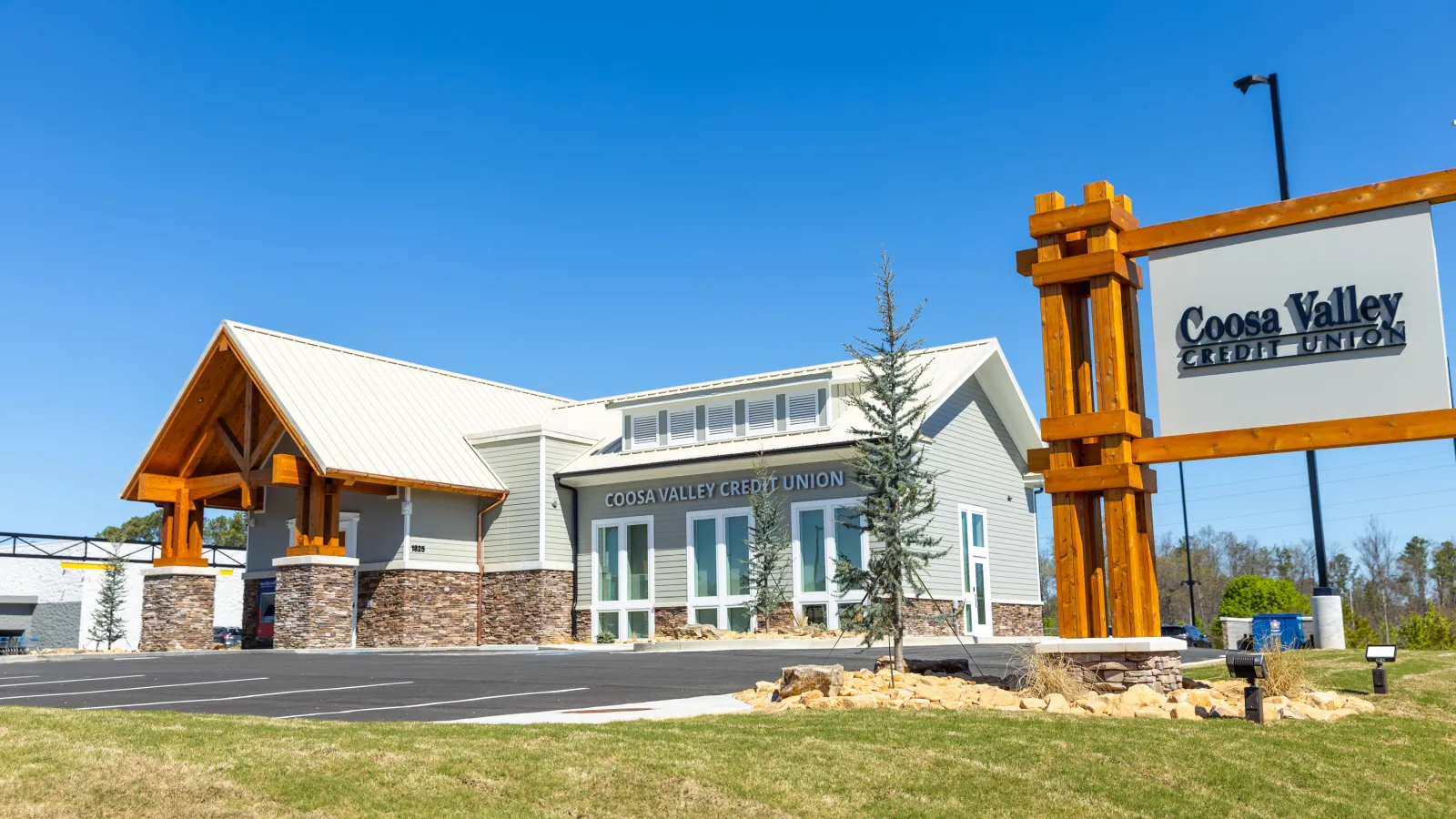 Coosa Valley Credit Union building with wooden sign and clear blue sky on a sunny day.
