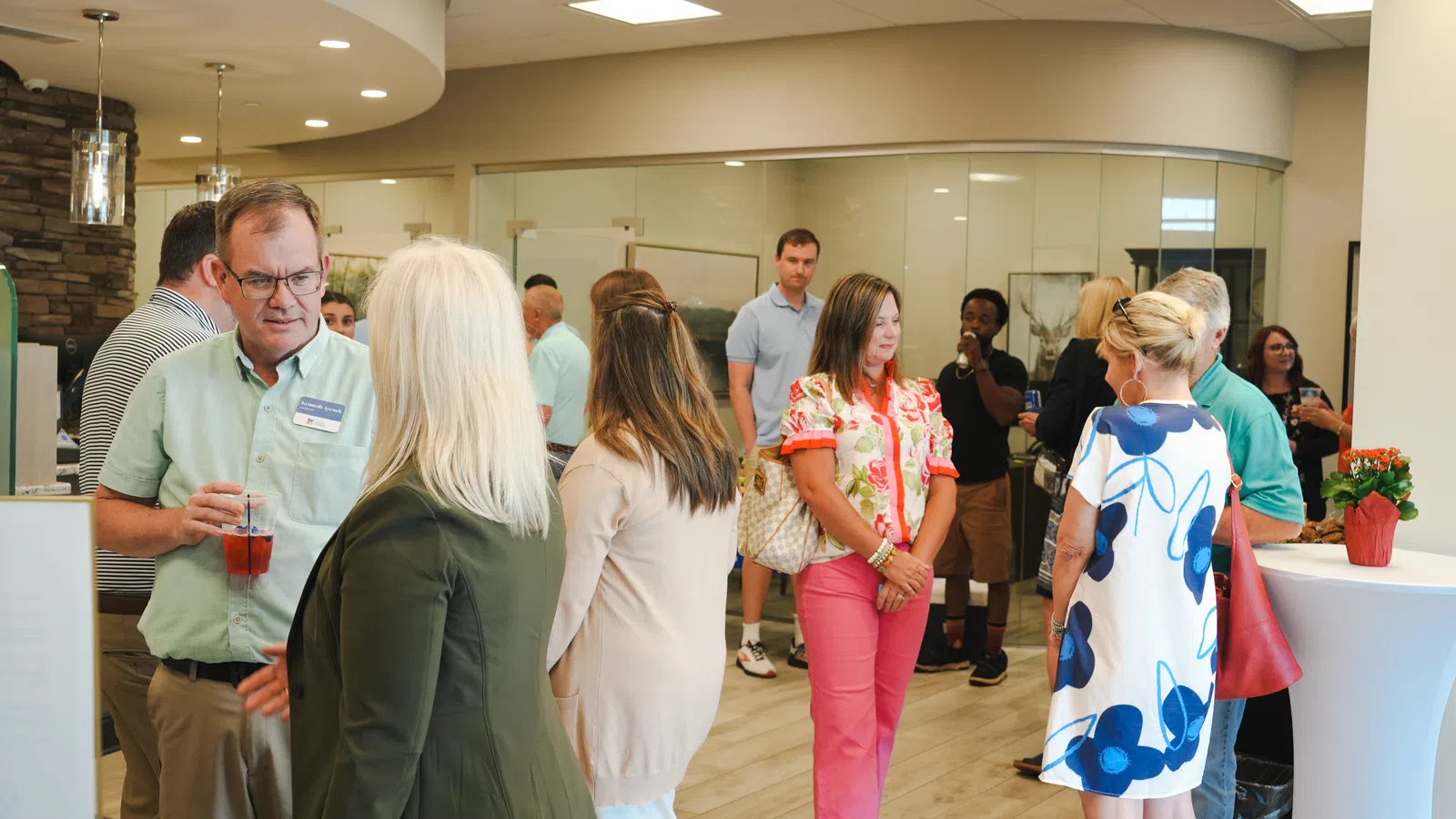 People socializing in a modern indoor space with casual attire and drinks during a networking event.