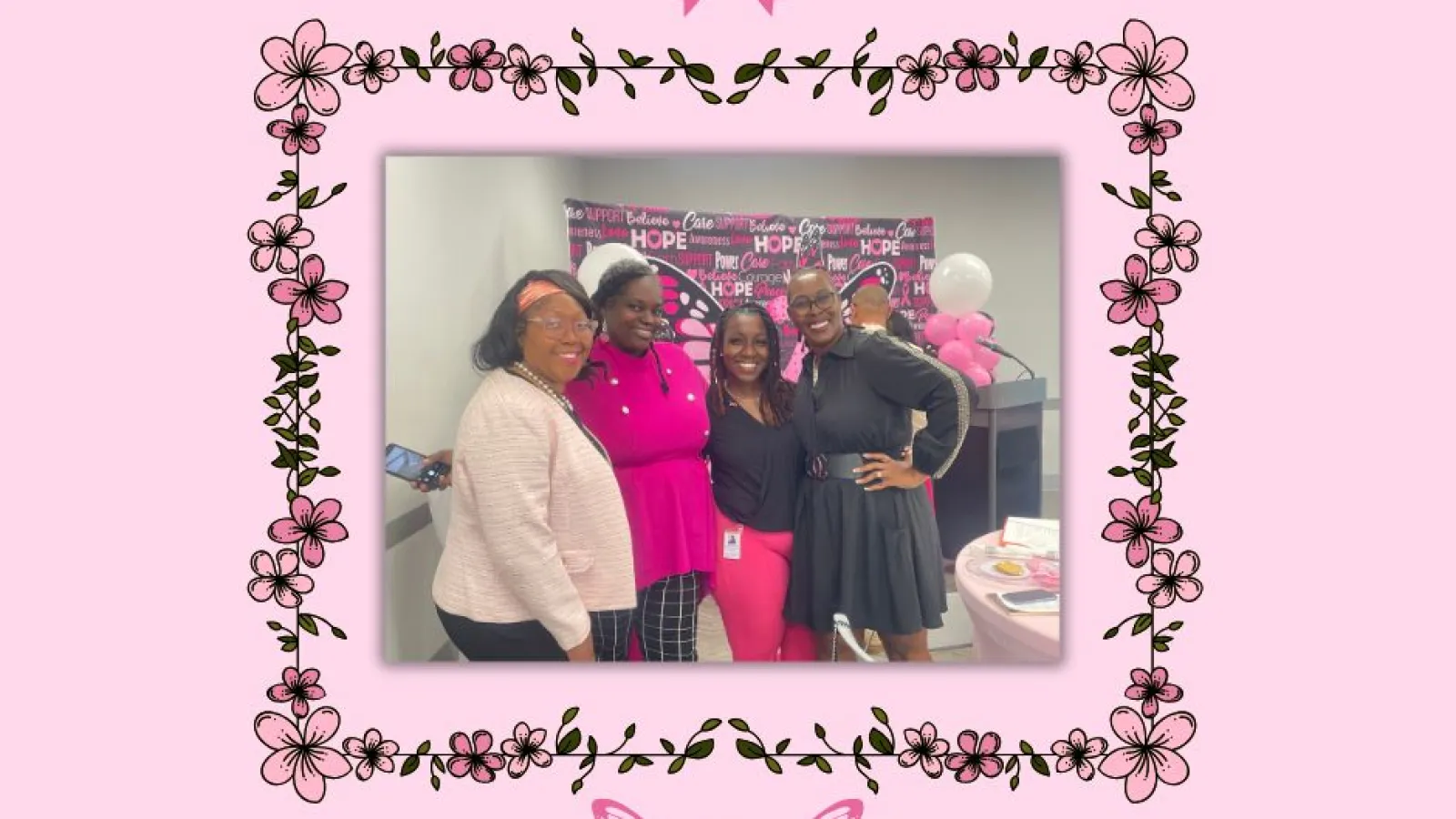 Four women smiling at a breast cancer awareness event with pink ribbons and floral border design.