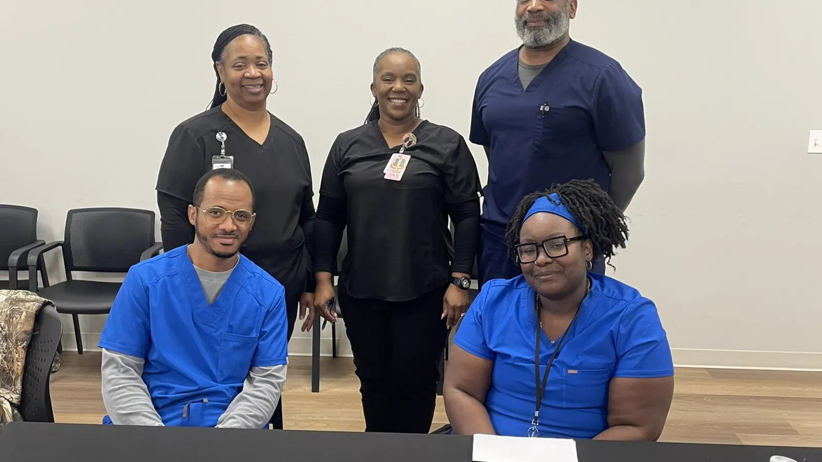 Healthcare professionals posing behind a table with diabetes education materials and branded kits in a clinical setting.