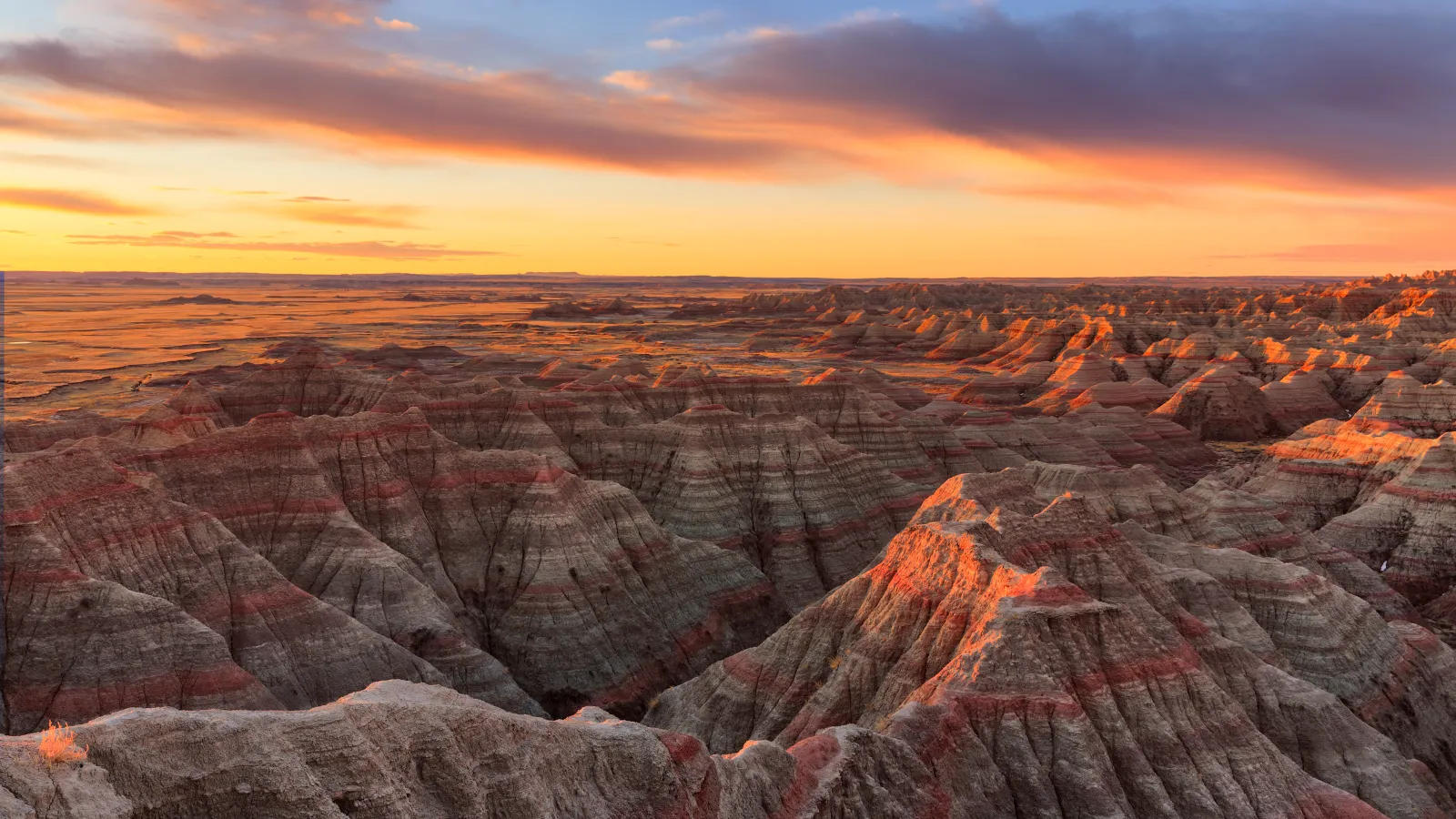 a large canyon with a sunset with Badlands National Park in the background
