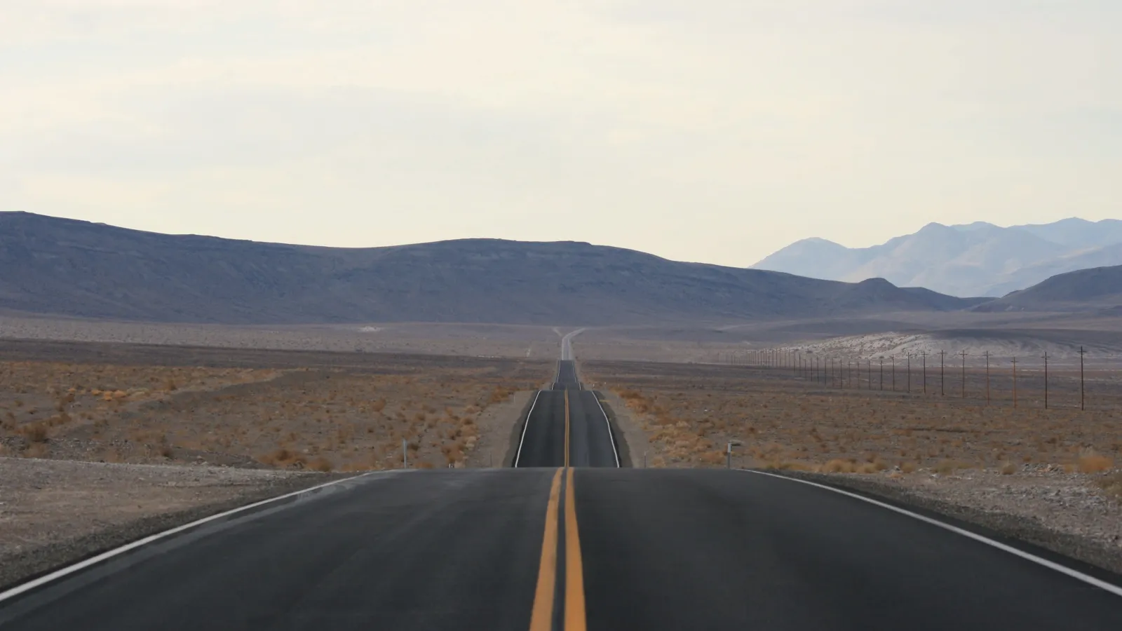 a long straight road with mountains in the background in California