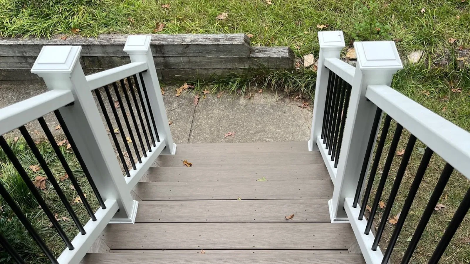 Close-up of green shingle siding on a house with a window and bare tree branches in the background.