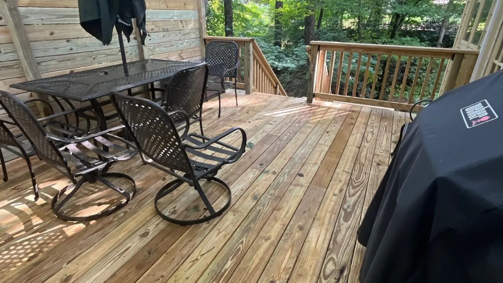 Close-up of green shingle siding on a house with a window and bare tree branches in the background.