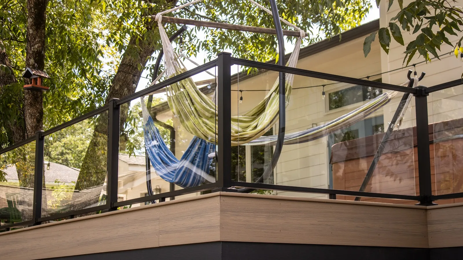 White house dormer windows with black roof shingles surrounded by green trees under blue sky.