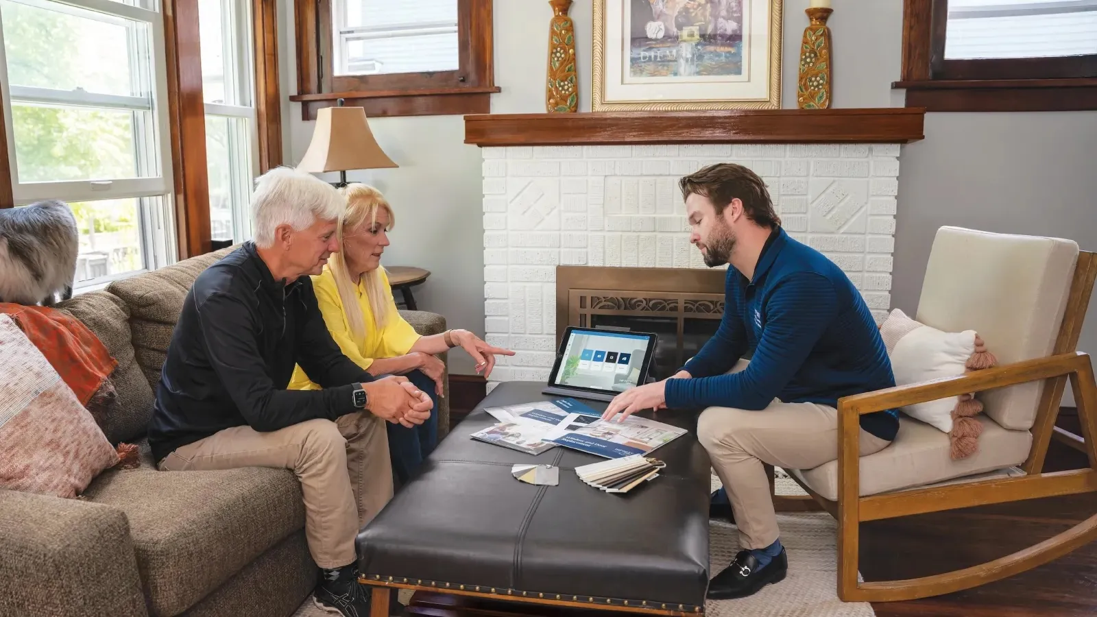 Real estate agent showing home design options to a senior couple in a cozy living room setting.