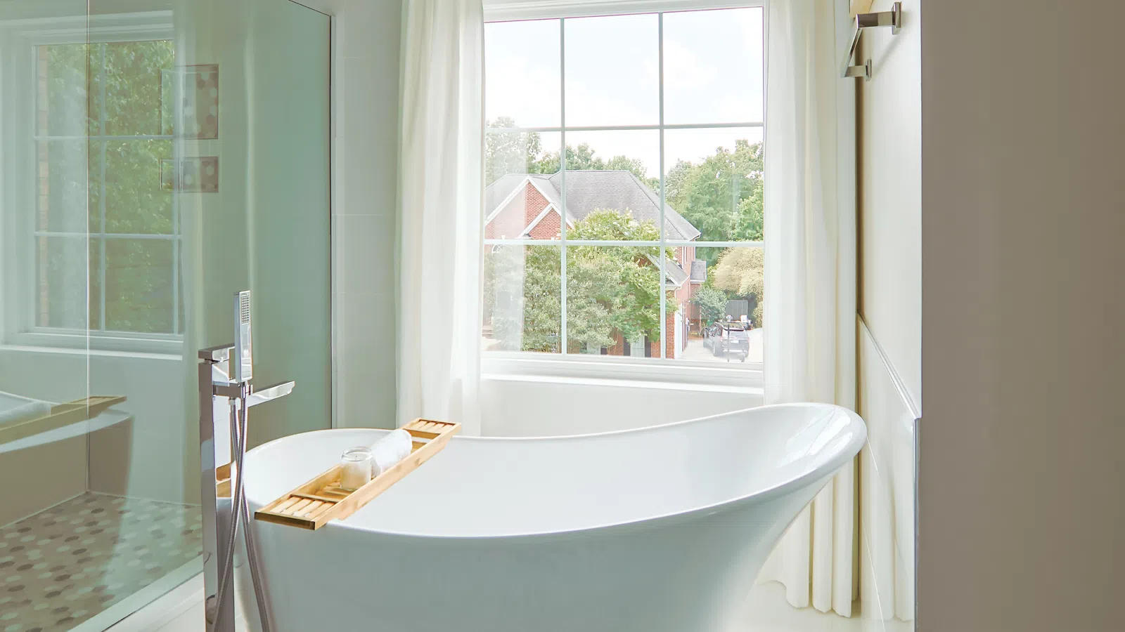 Elegant bathroom with a freestanding tub and large window showcasing lush greenery outside.