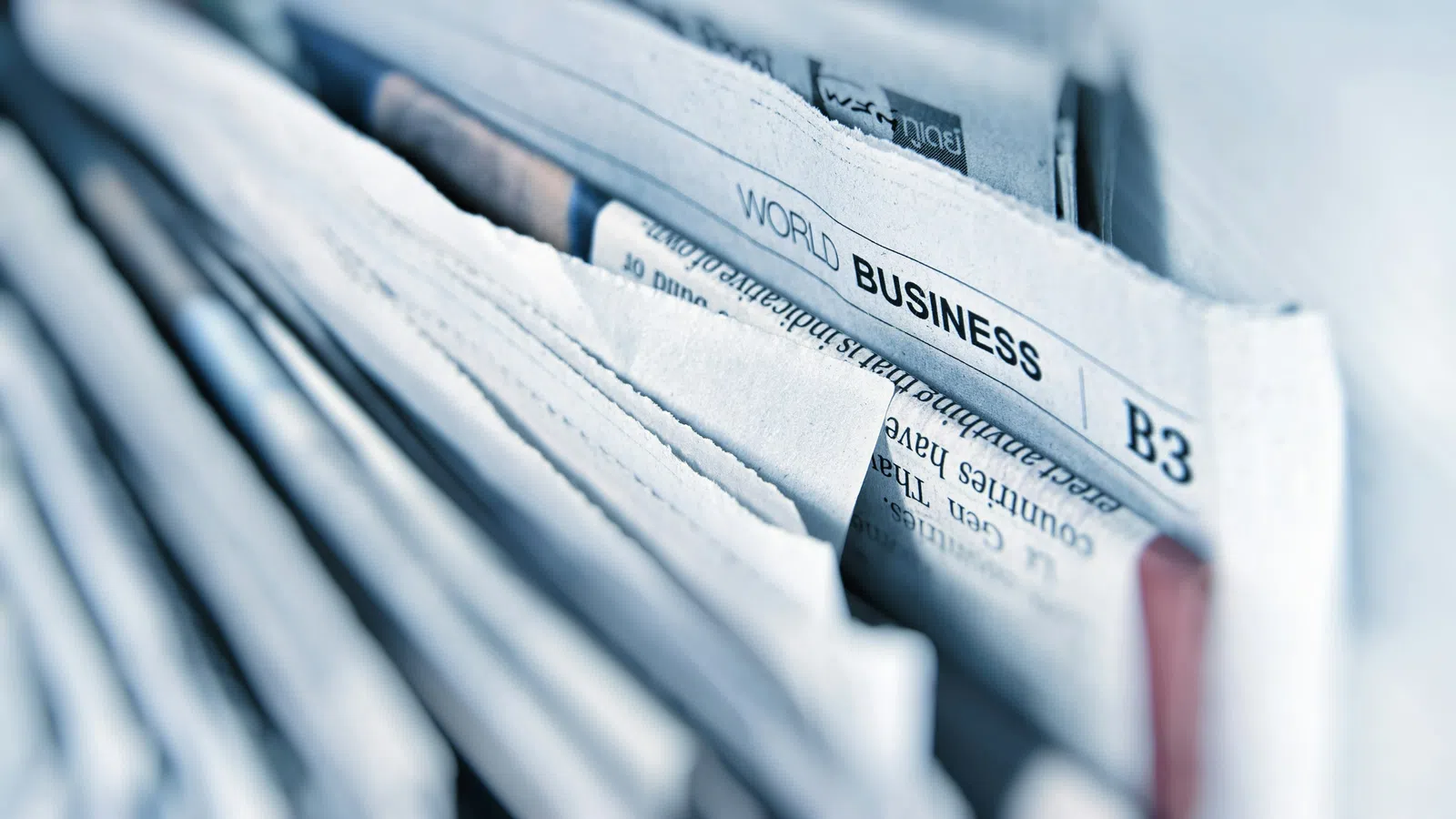 Close-up of folded newspapers with visible overlaid text section titled World Business B3.