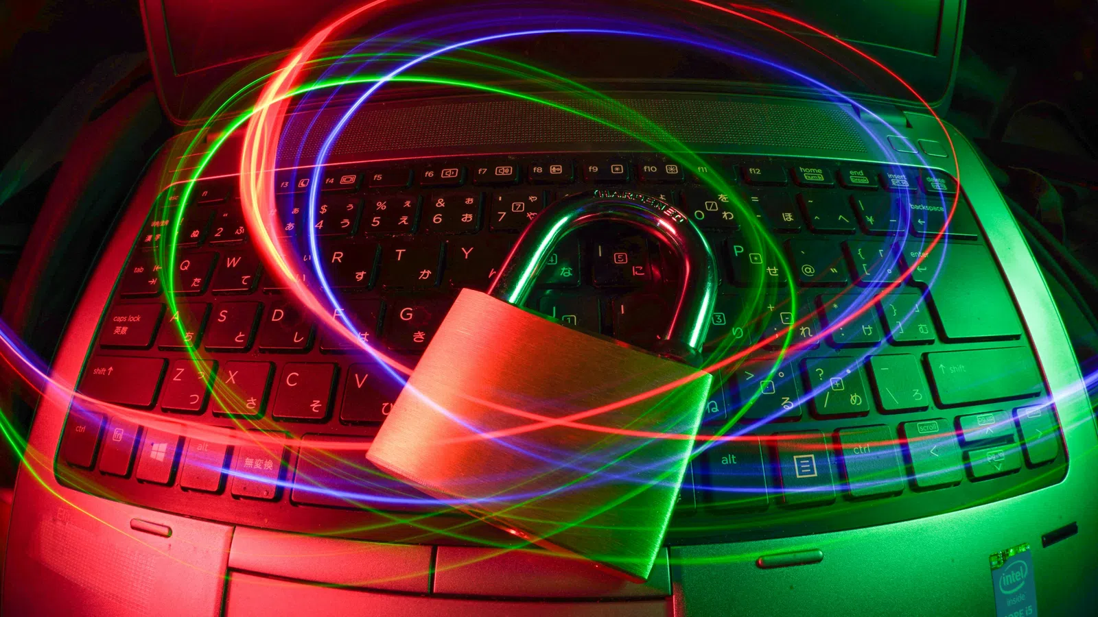 Metal padlock on laptop keyboard with swirling red, blue, and green light trails symbolizing cybersecurity and data protection.