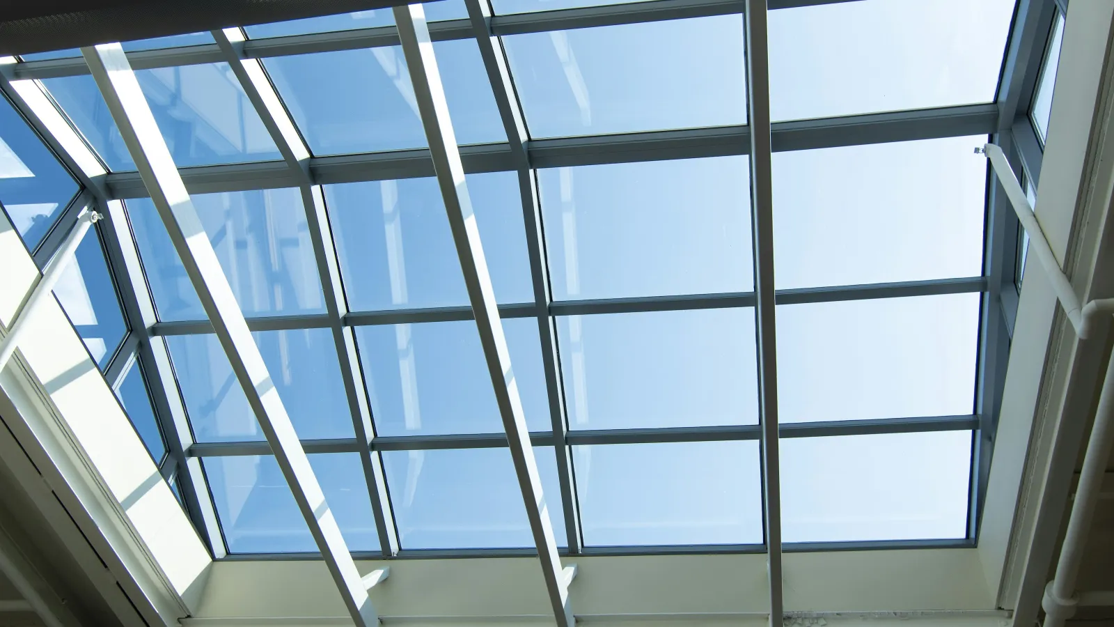 Bright skylight view with glass panels and blue sky, illuminating modern space below.