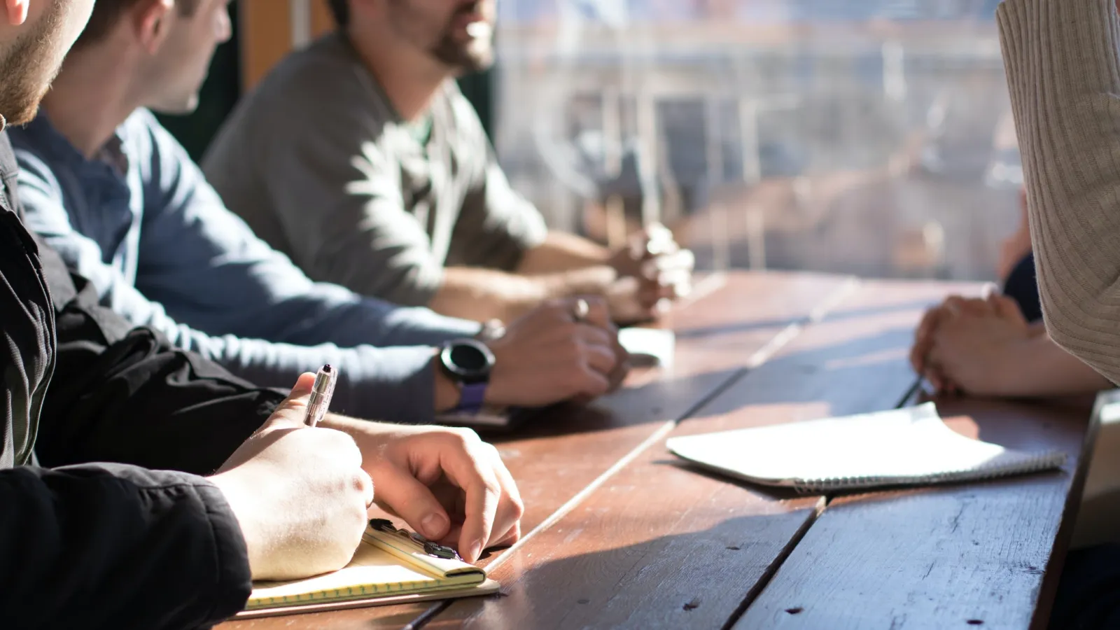 a group of people sitting at a table writing on paper