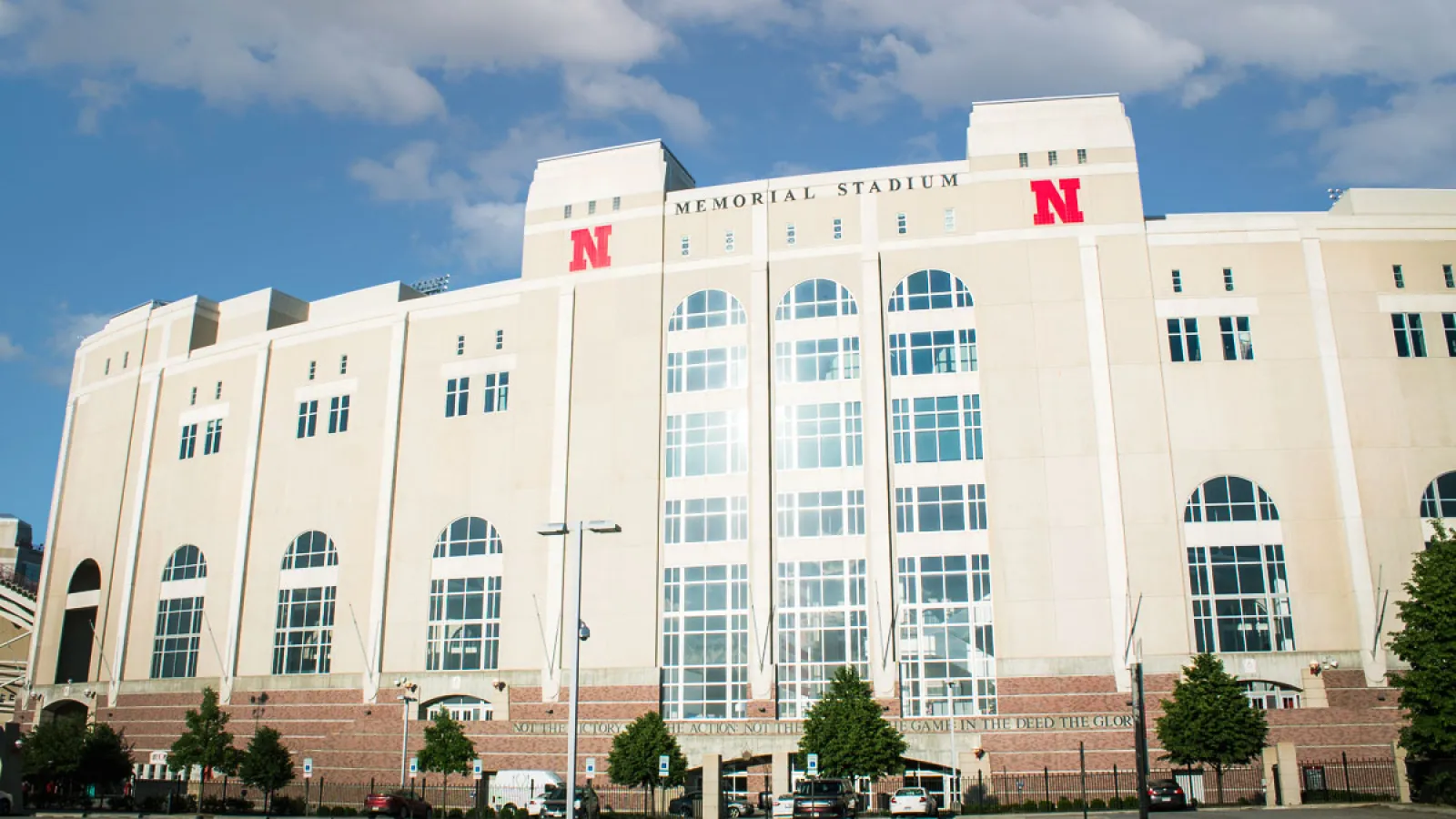 a large white building with a flag on top with Memorial Stadium in the background