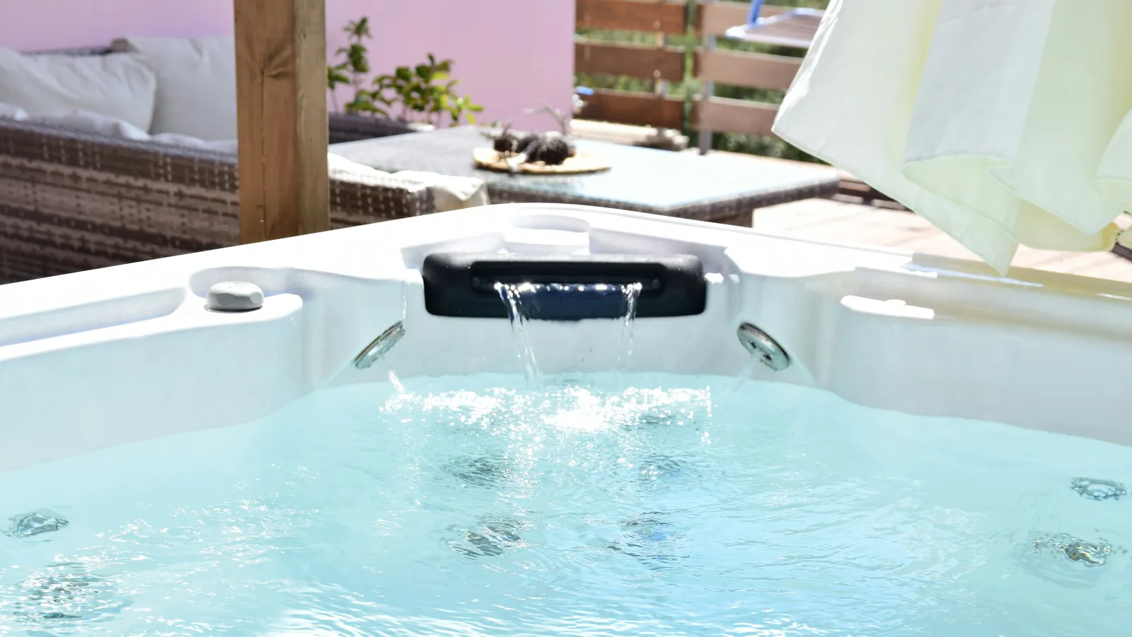 Outdoor hot tub filled with clear water and flowing waterfall feature in a cozy patio setting.