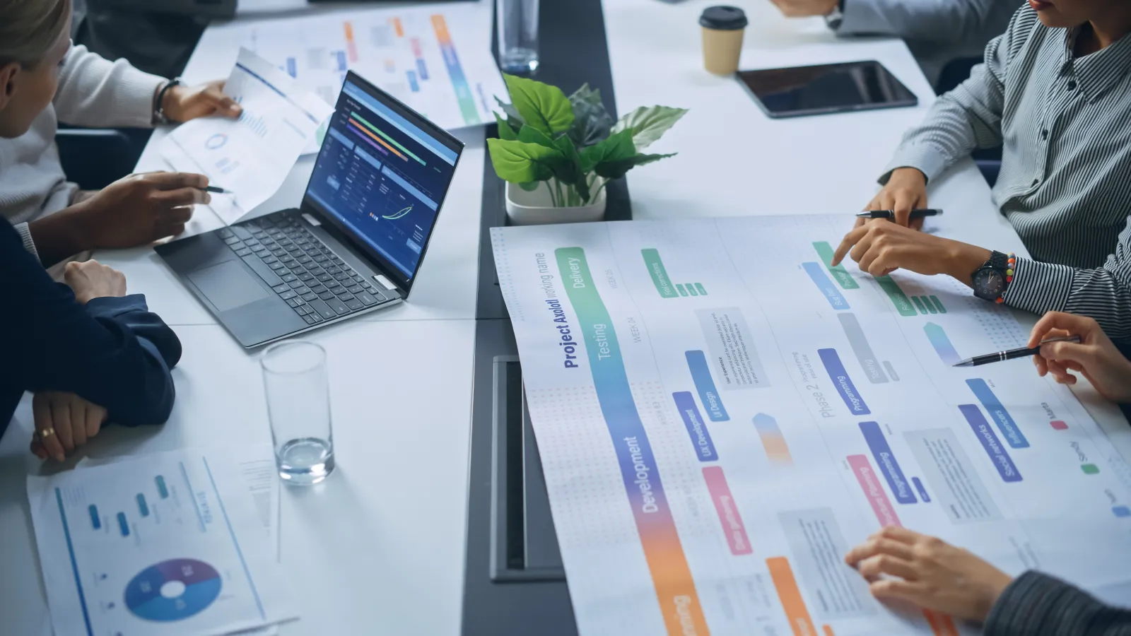Team reviewing project plan and charts on large paper and laptop during a business meeting