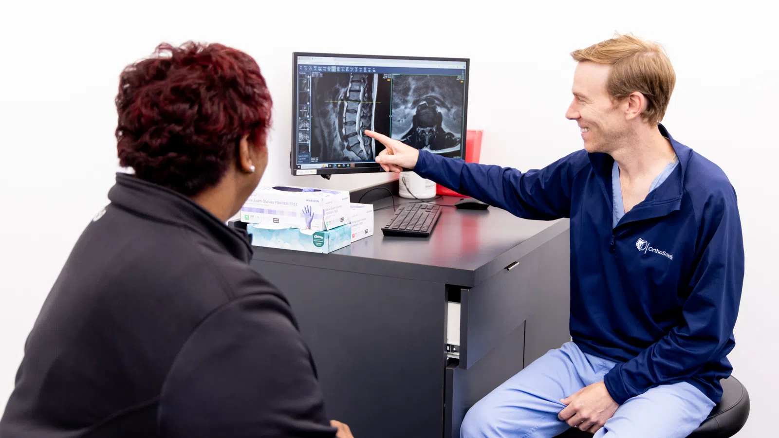 A healthcare professional discussing imaging results with a patient in a modern clinic setting.