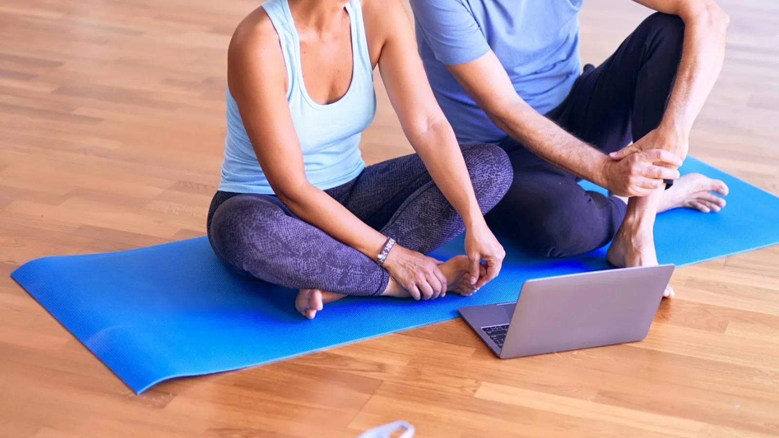 a man and a woman sitting on a mat on a wood floor