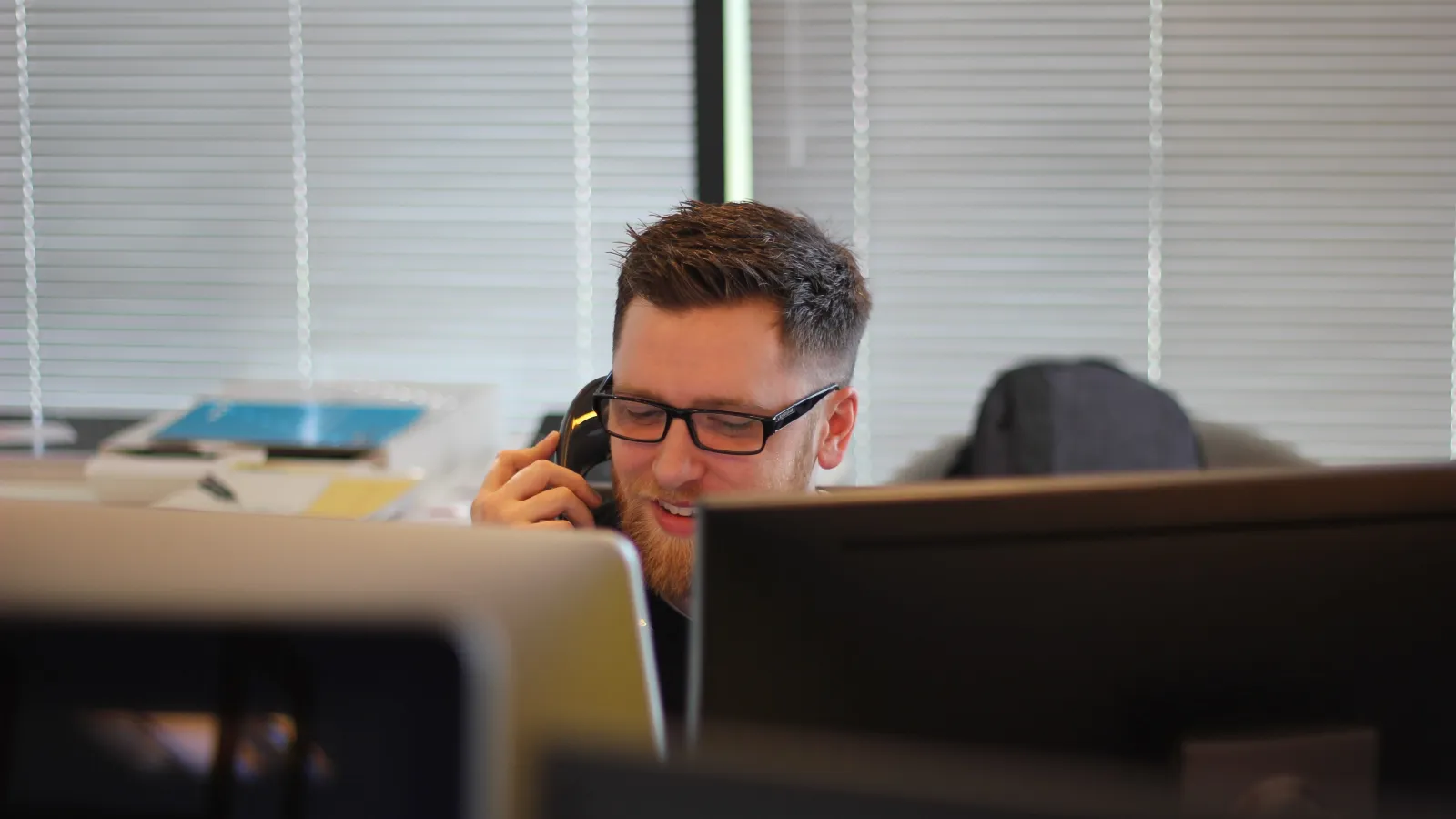 a man with a phone in his hand sitting at a desk