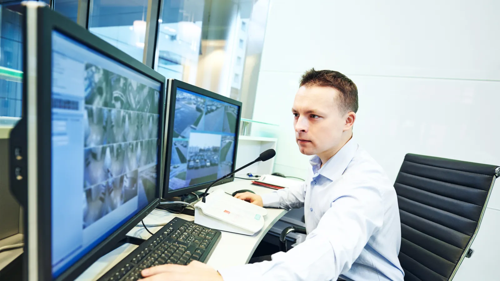 a person sitting at a desk with a computer and a microphone
