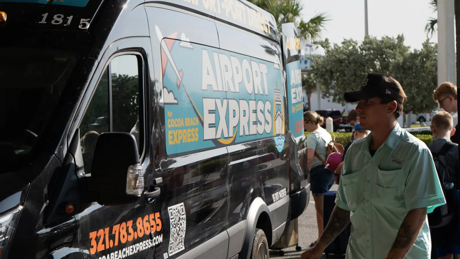 Airport Express shuttle van parked with people boarding under bright daylight near palm trees.
