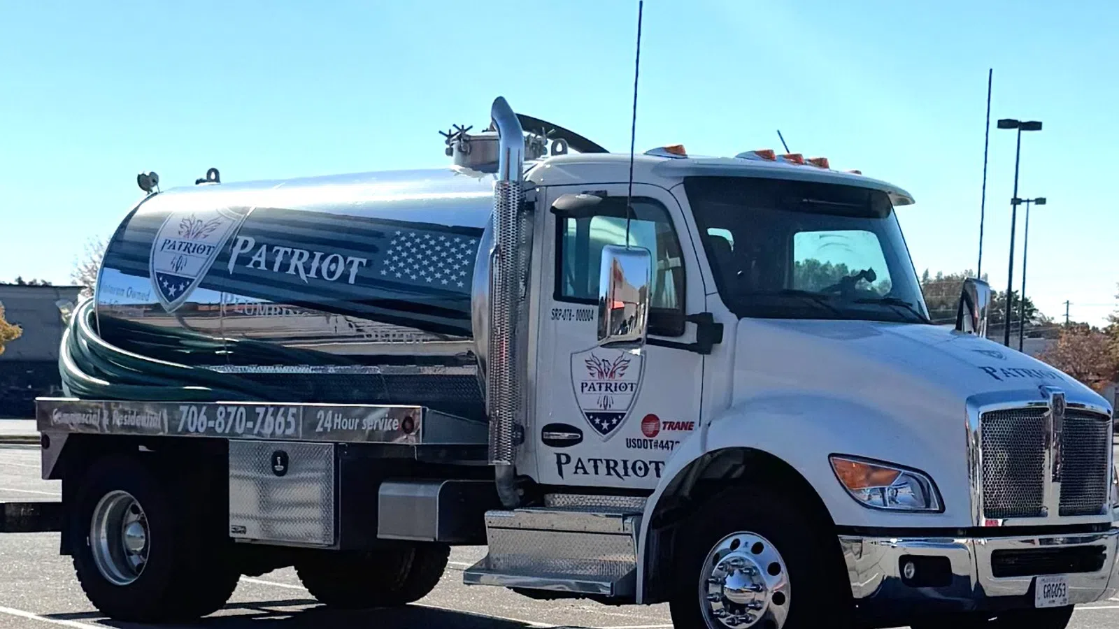 White Patriot branded tanker truck parked in a lot under clear blue sky.
