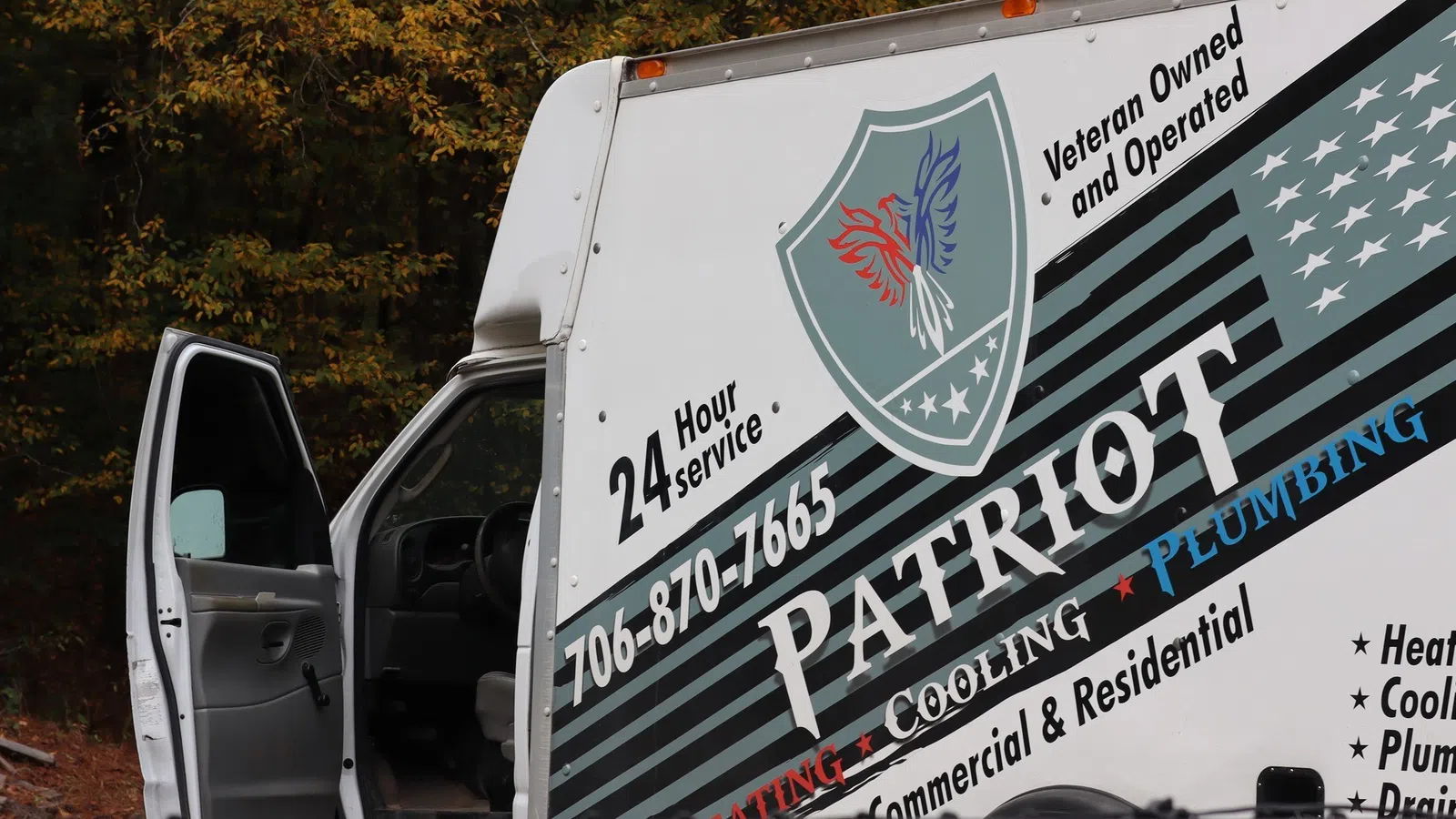 Patriot service van with heating, cooling, and plumbing logo and contact number parked with open door.