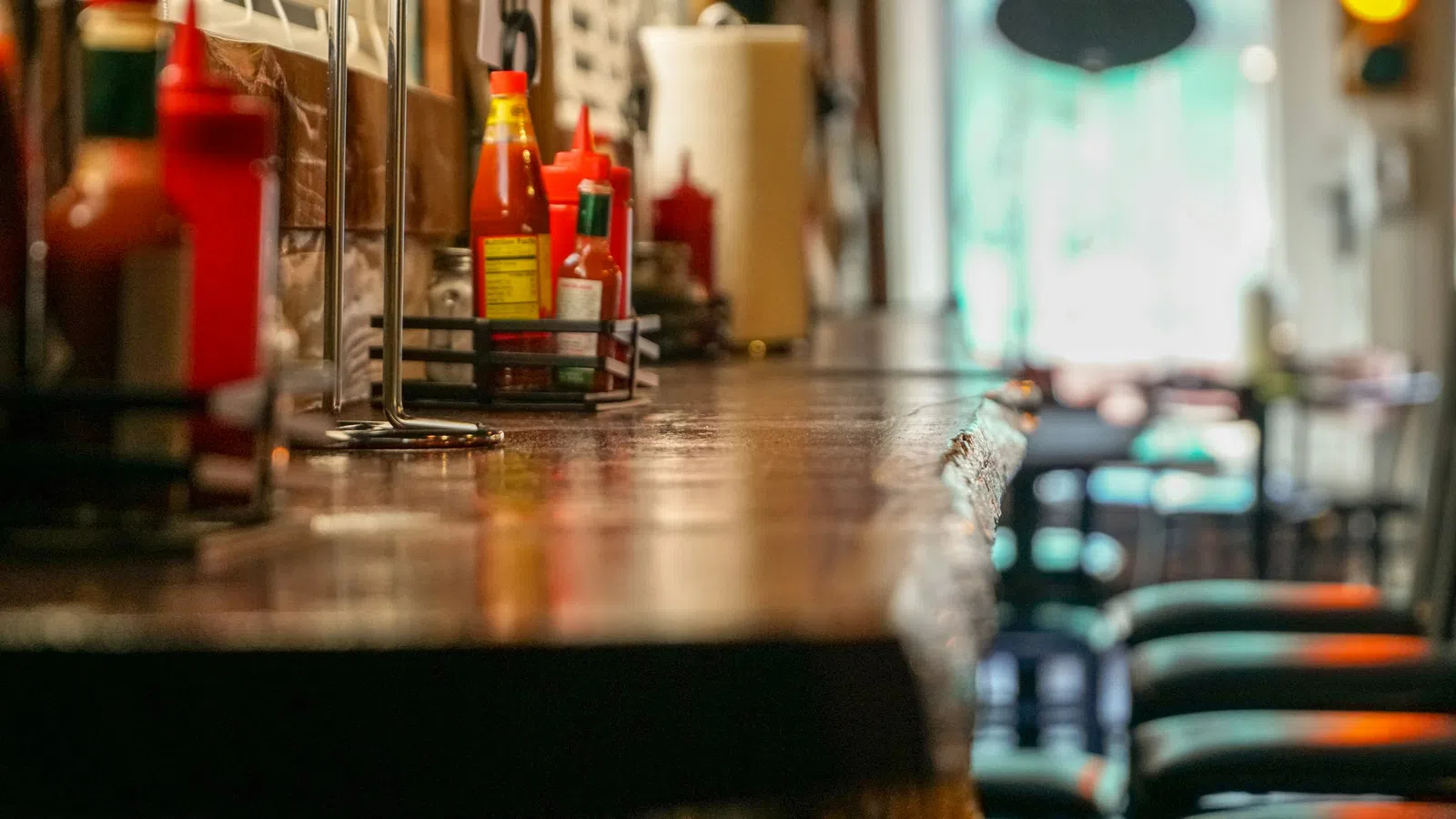 Close-up of a diner counter with condiments and stools in a softly lit restaurant interior