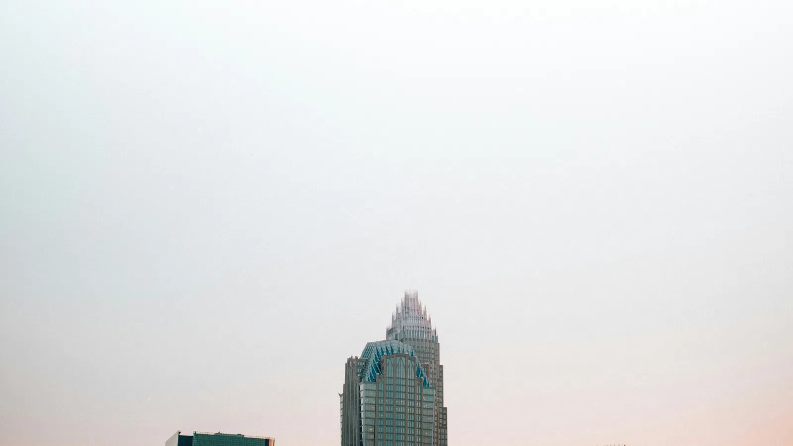 Modern city skyline at sunset with tall skyscrapers and glowing orange sky in the background