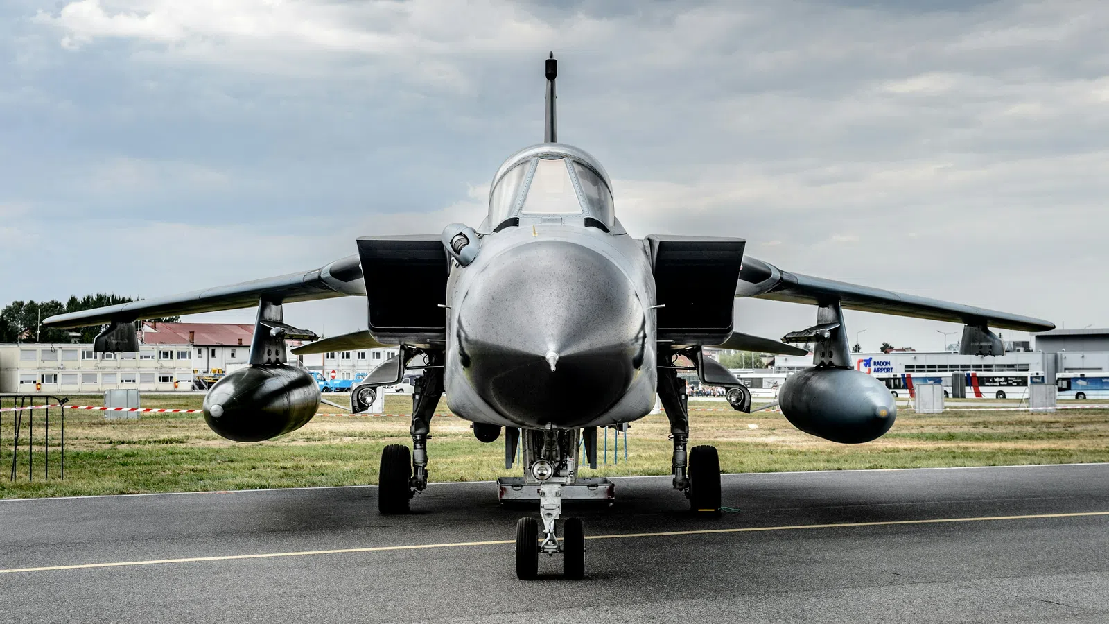 Front view of a military jet fighter parked on a runway under a cloudy sky