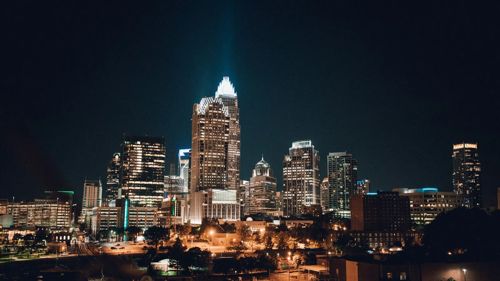 Charlotte city skyline at night with illuminated skyscrapers and glowing streetlights under clear sky.