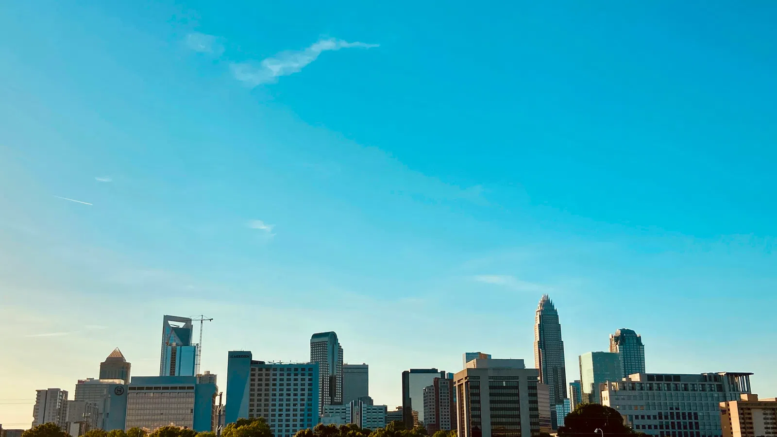 Skyline of a modern city with tall buildings under a clear blue sky at sunset.