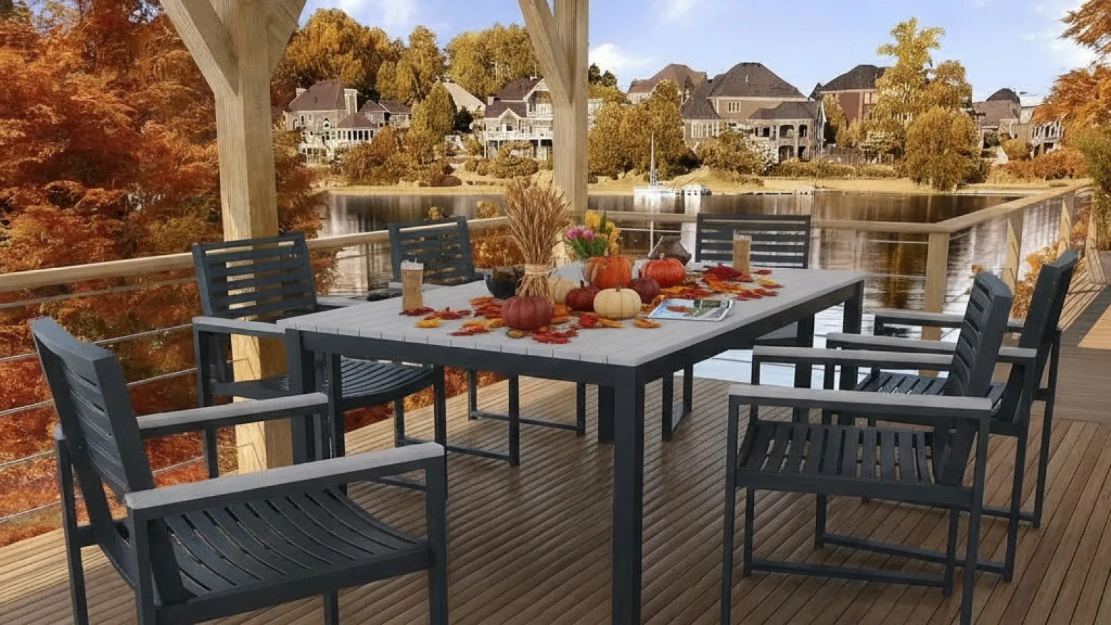 Outdoor dining area with black chairs and table decorated with autumn pumpkins on wooden deck overlooking lake and fall foliage.