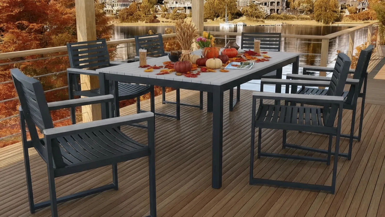 Outdoor dining area on wooden deck with black chairs and fall-themed table decor overlooking lake and houses