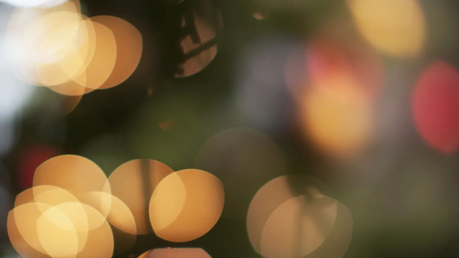 Soft golden and colorful bokeh lights creating a warm, festive, and blurred background effect.