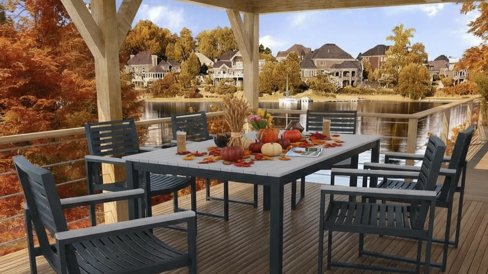 Outdoor dining area on wooden deck with black chairs and fall-themed table decor overlooking lake and houses