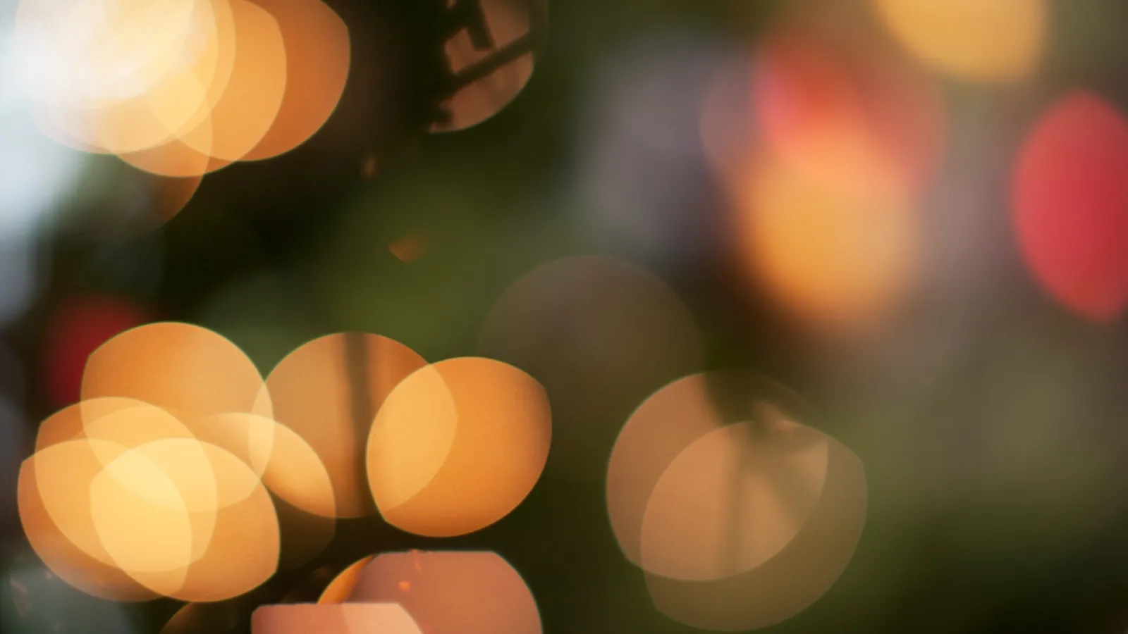 Blurred warm yellow and orange bokeh lights on a dark background creating a soft glowing effect.