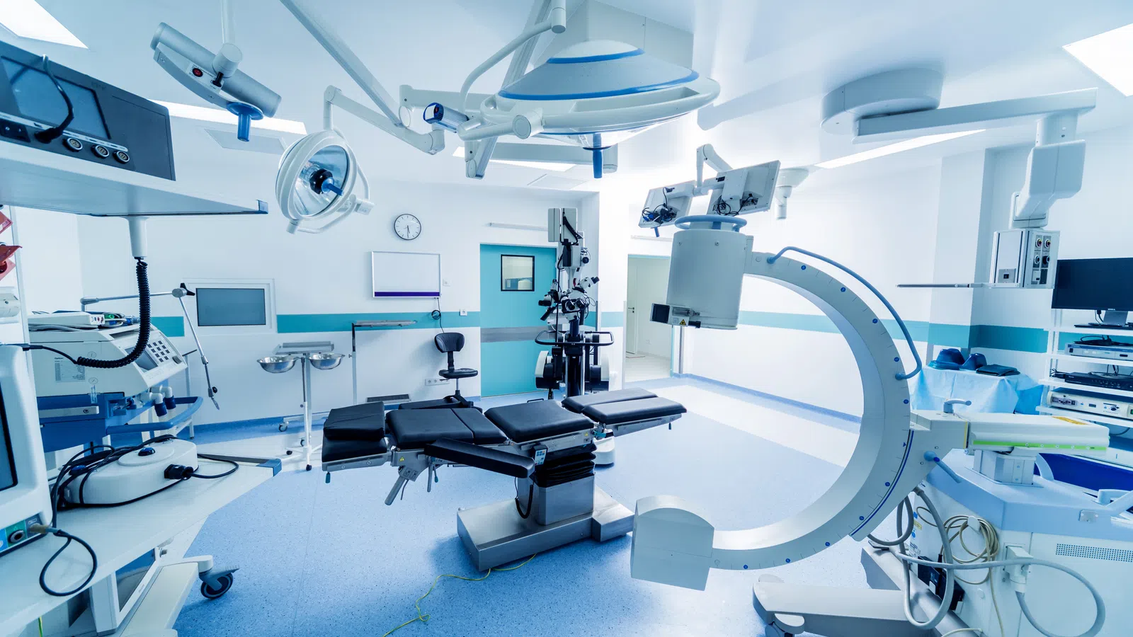 Bright, modern operating room with surgical table, lights, monitors, and advanced medical equipment ready for surgery.