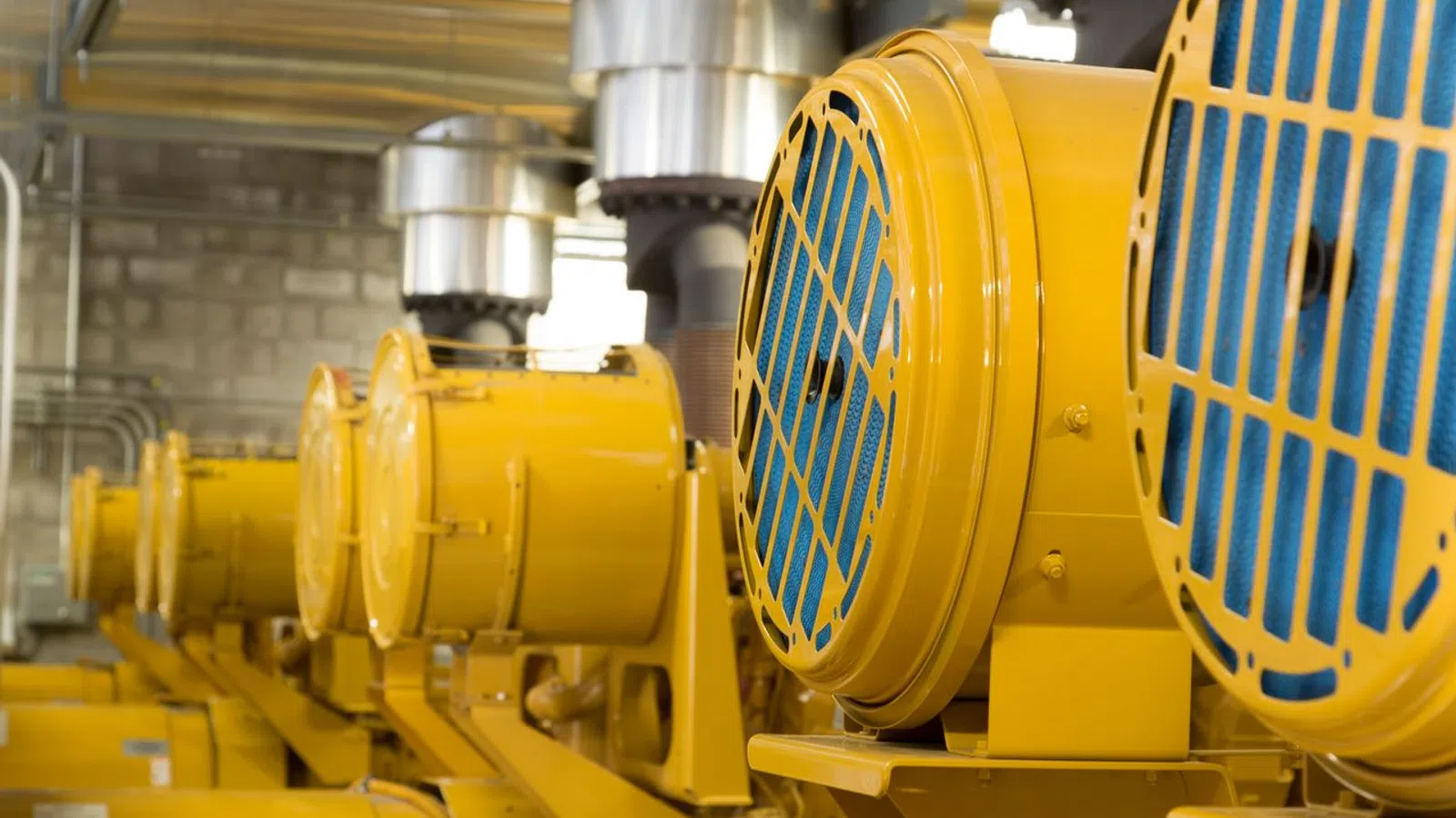 Close-up of industrial yellow machinery with blue grills arranged in a factory setting.