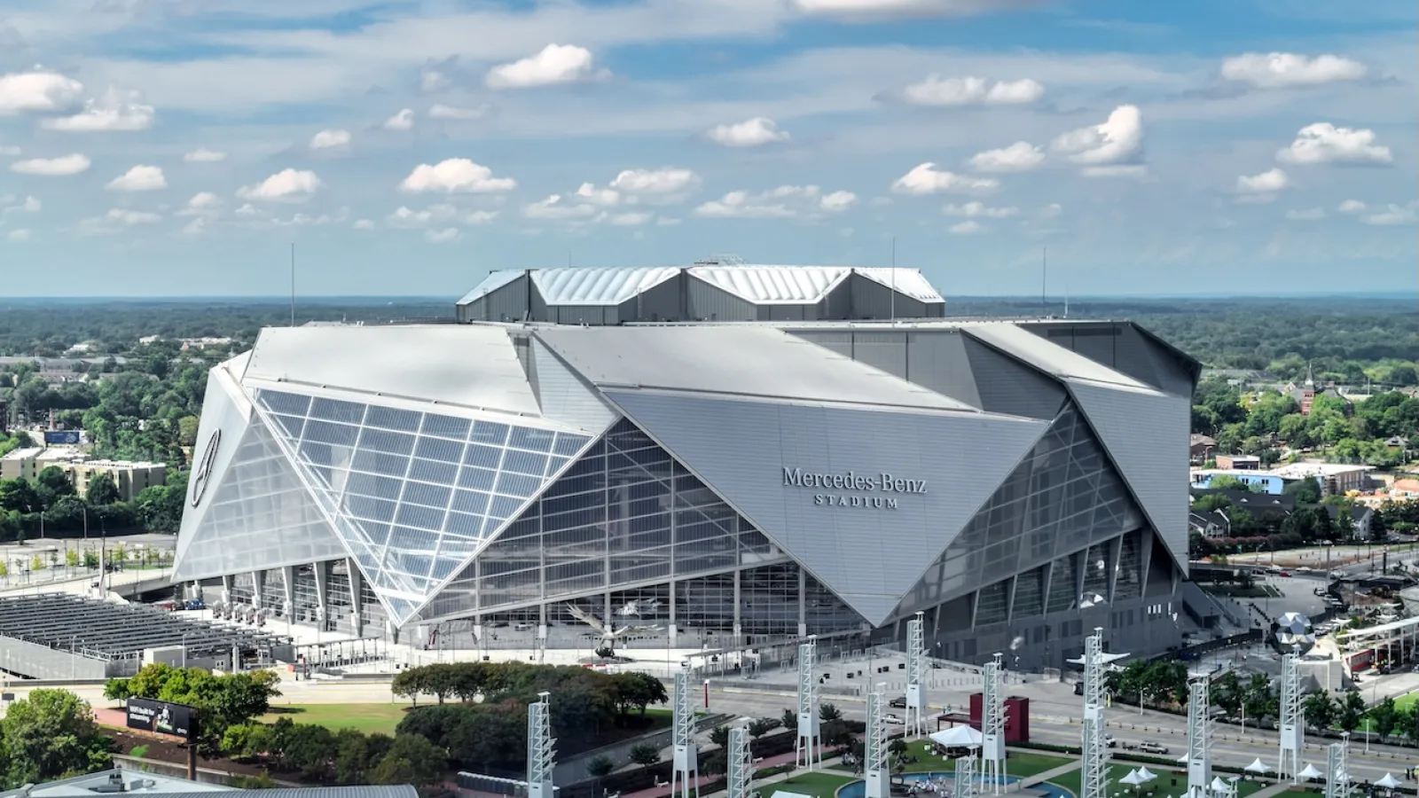 Mercedes-Benz Stadium in Atlanta with its modern angular roof and clear blue sky above.