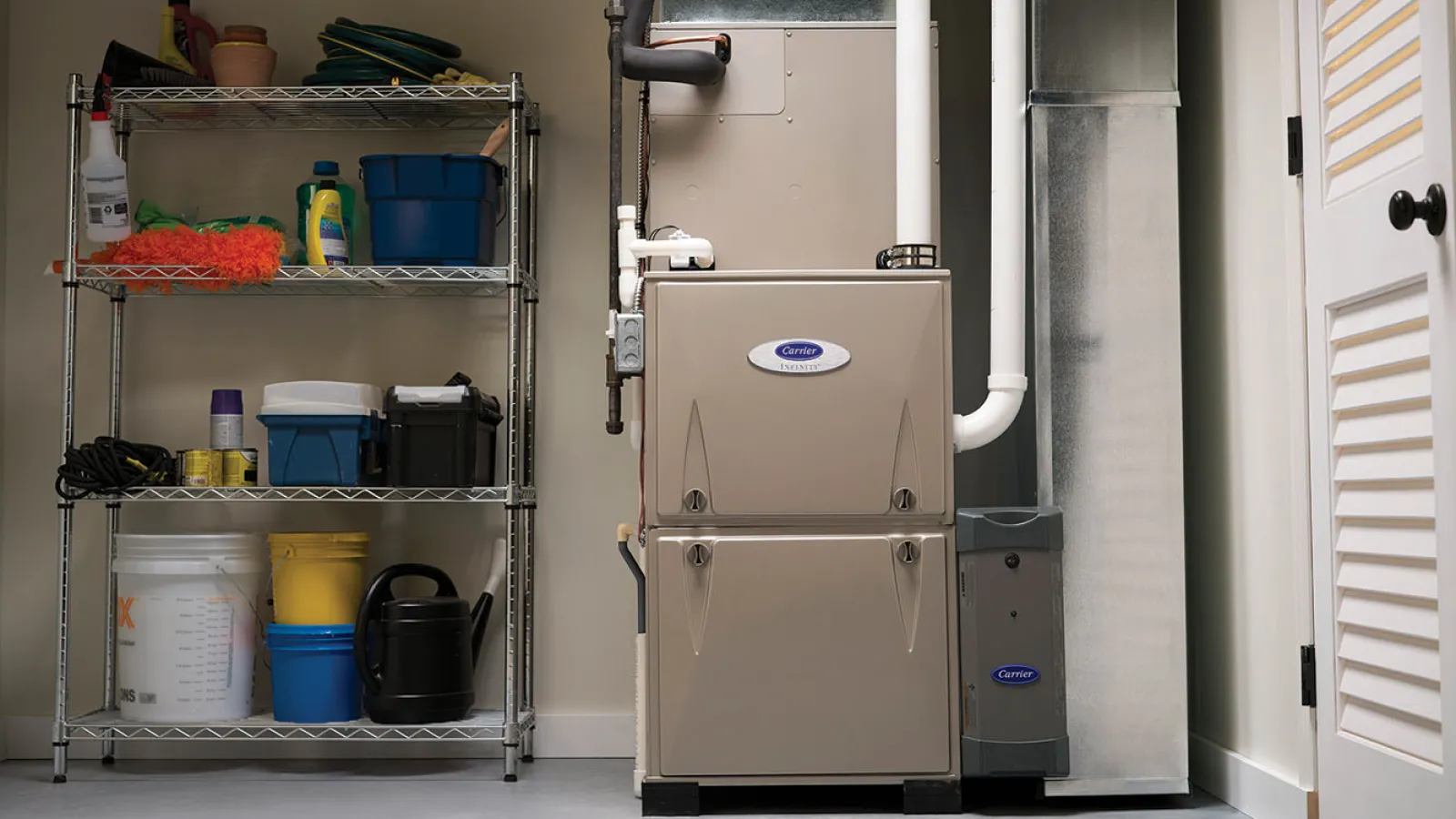 Utility room with a Carrier furnace unit beside metal shelving holding cleaning and gardening supplies