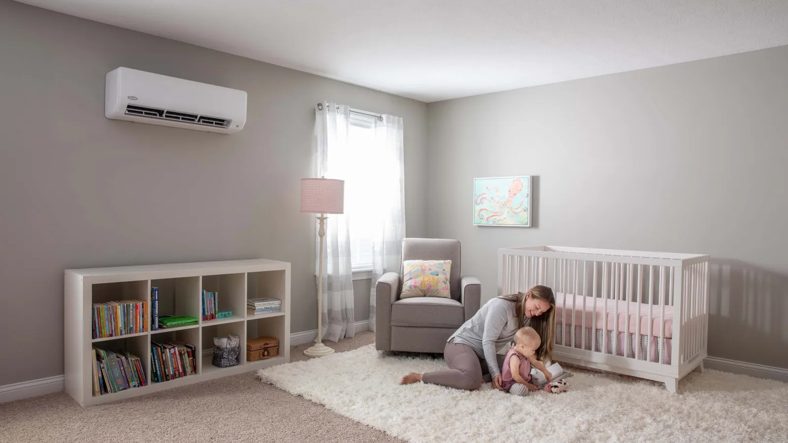 Mother playing with toddler on soft rug in bright, cozy nursery with crib, armchair, and bookshelf.