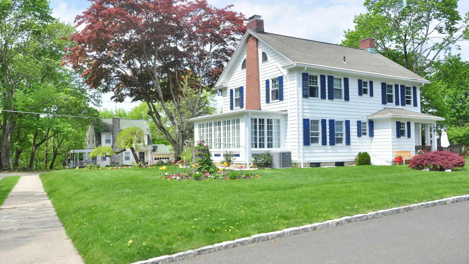 a large white house with a lawn and trees in front of it